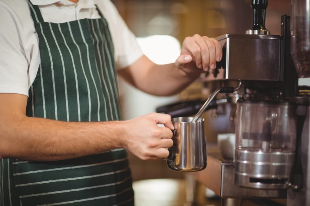 Barista Steaming Milk At The Coffee Machine